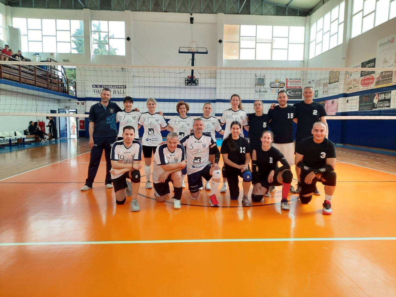 Two teams posing together on the volleyball court